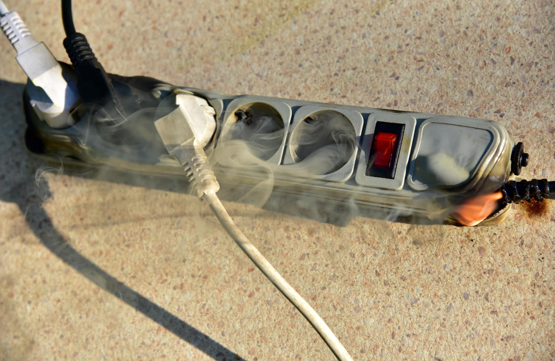 A smoking power strip starts to catch fire.