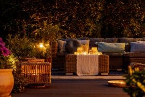 An outdoor patio with a couch and several sources of lighting, creating an ambient atmosphere.