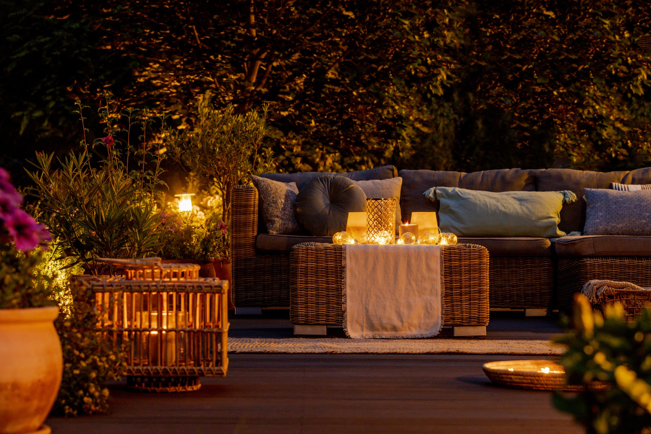 An outdoor patio with a couch and several sources of lighting, creating an ambient atmosphere.