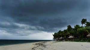 A beach as a tropical storm rolls in with strong winds and dark clouds.