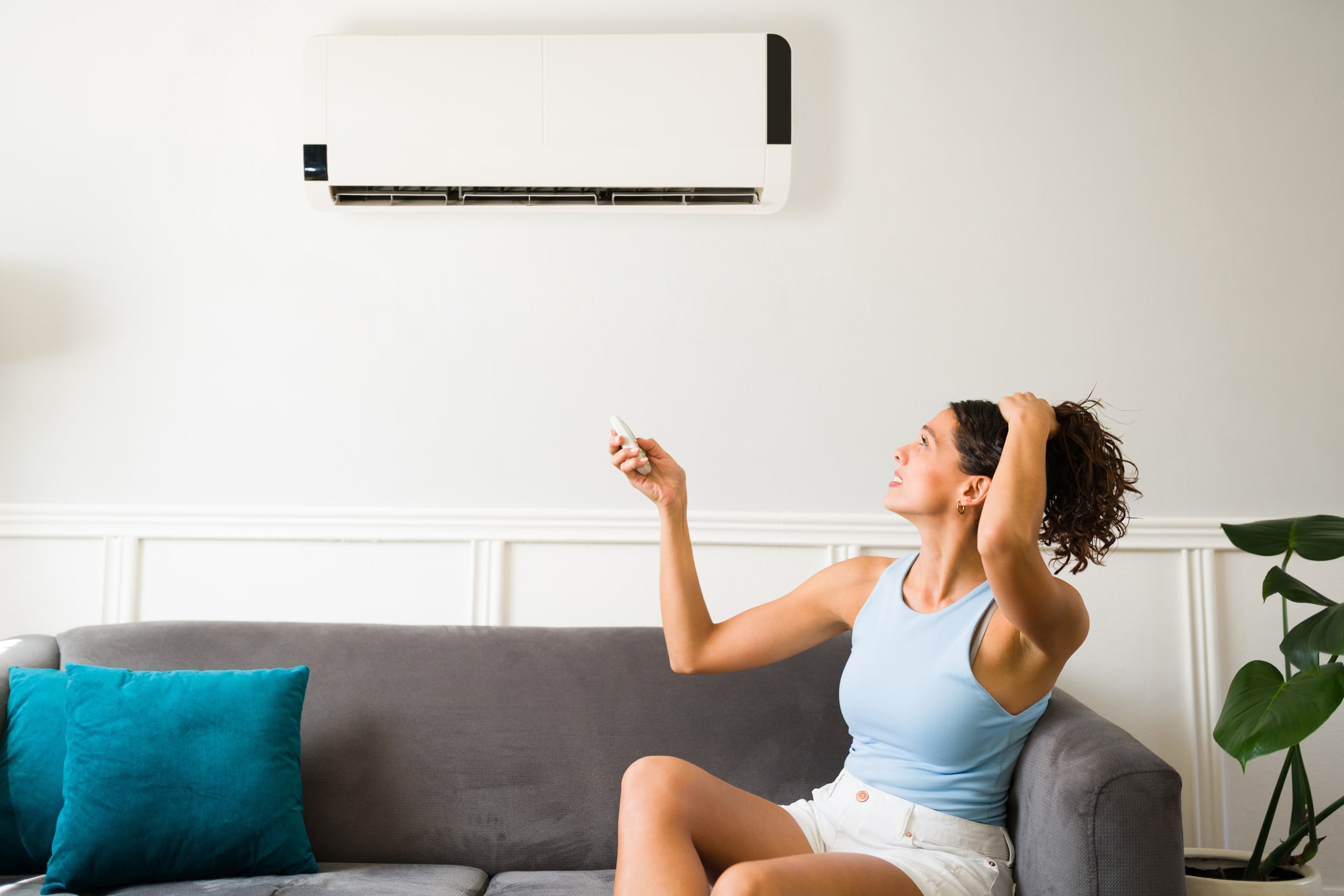 Woman troubleshooting a wall-mounted AC unit at home, representing Electric City's HVAC electrical repair services in Katy, TX.