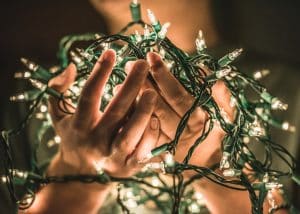 A pair of hands holding a bundle of white Christmas lights.