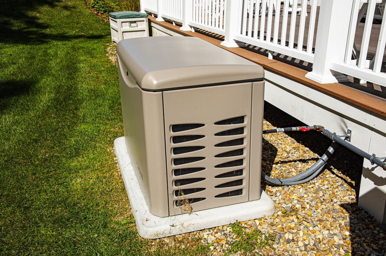 A new generator sitting outside of a house on a concrete slab.