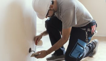 Electrician Installing Electrical Outlets In A Modern Home, Ensuring Safe And Accurate Wiring On A White Wall.
