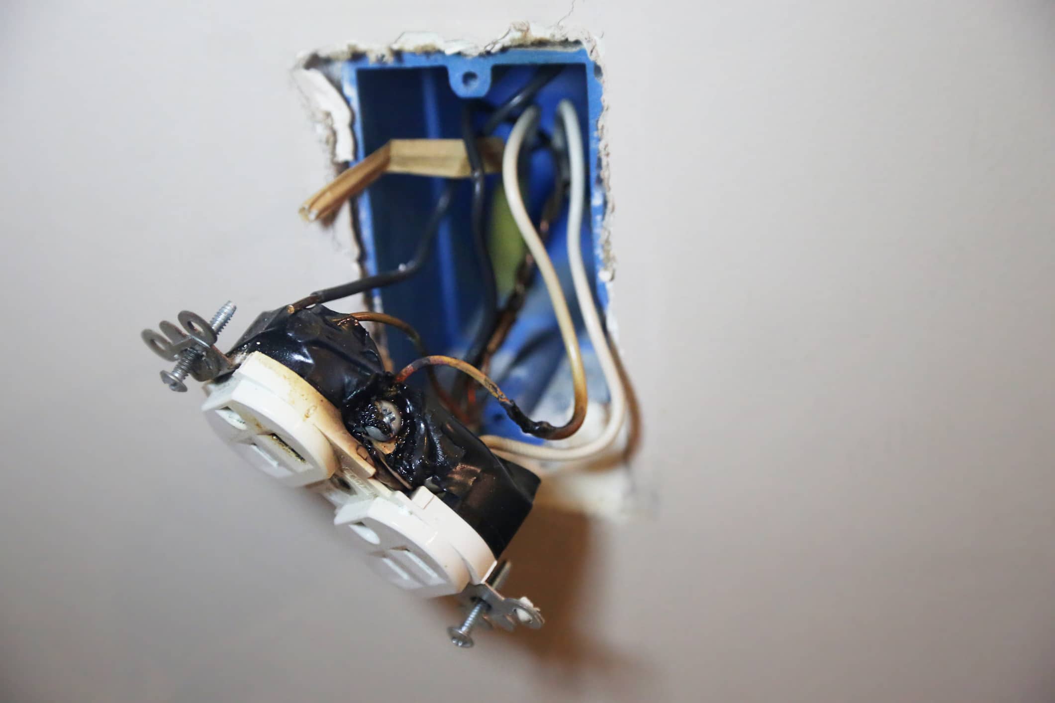 Wall outlet with burned wires and melted plastic