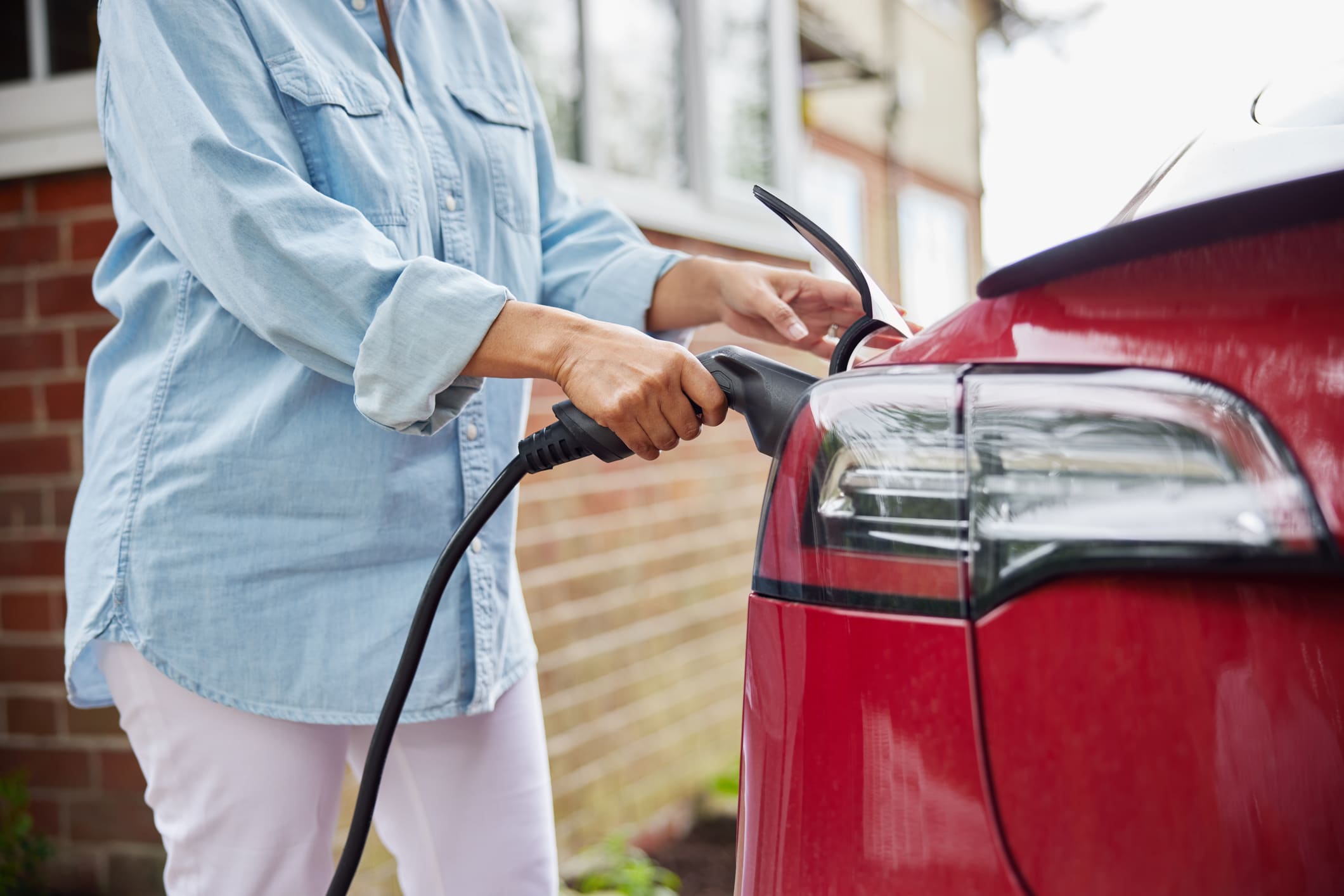 A woman charging her electric vehicle safely at home, highlighting the importance of preparation before EV charger installation.