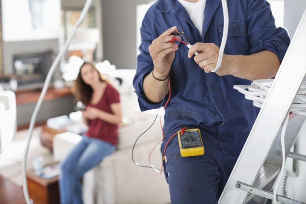 An electrician inspecting home’s wiring, showing a pro is sometimes needed to diagnose issues and repairs. 