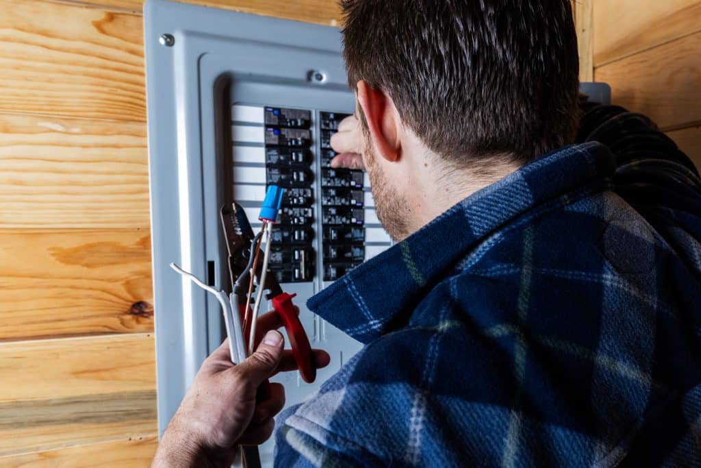 Someone examining wiring inside a home electrical panel to check for hidden problems.